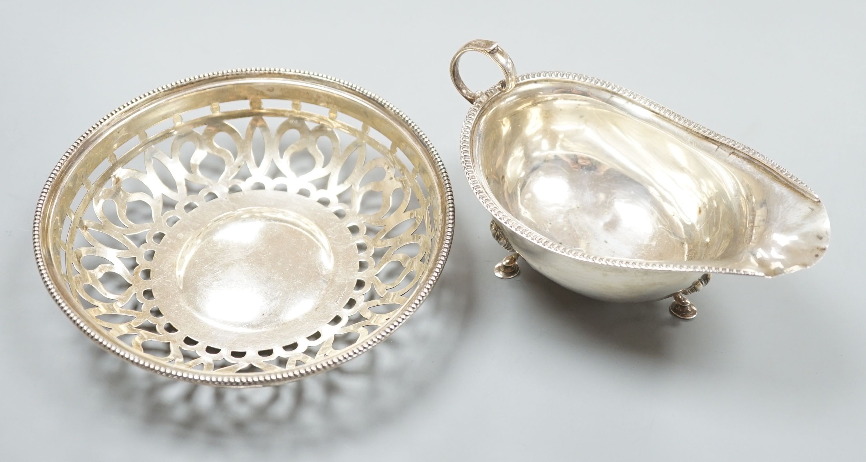 An oval sauce boat with French gadroon rim and flying scroll handle, Birmingham 1918 and a pierced circular bowl with beaded rim, Birmingham 1910, diameter 15.25cm, 207 grams.